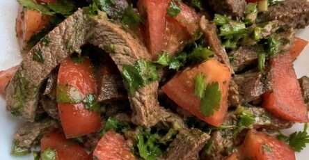 Salade fraîche au bœuf avec tomates, herbes fraîches et citron dans un grand saladier estival coloré