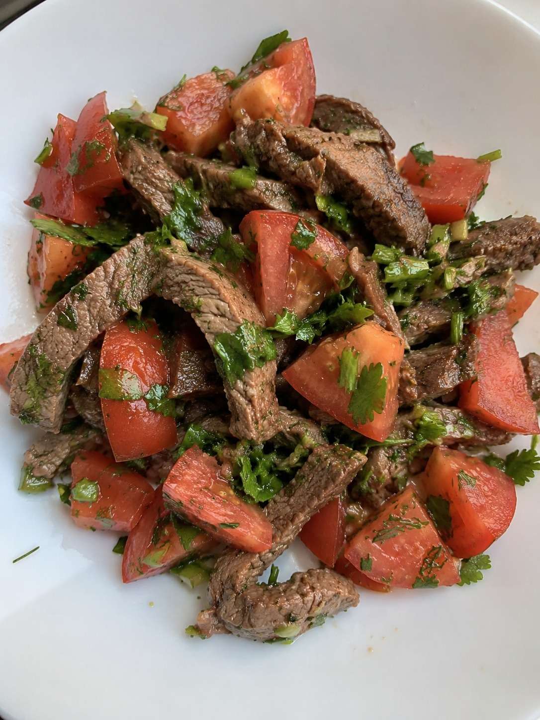 Salade fraîche au bœuf avec tomates, herbes fraîches et citron dans un grand saladier estival coloré