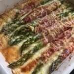 Gratin d’asperges vertes au jambon sec avec crème et fromage gratiné dans un plat rustique doré au four