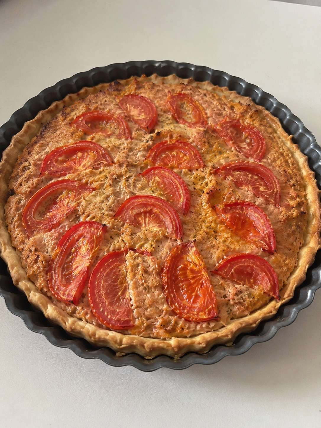 Tarte thon salée, tomates et moutarde avec fromage gratiné dans un moule rustique doré au four