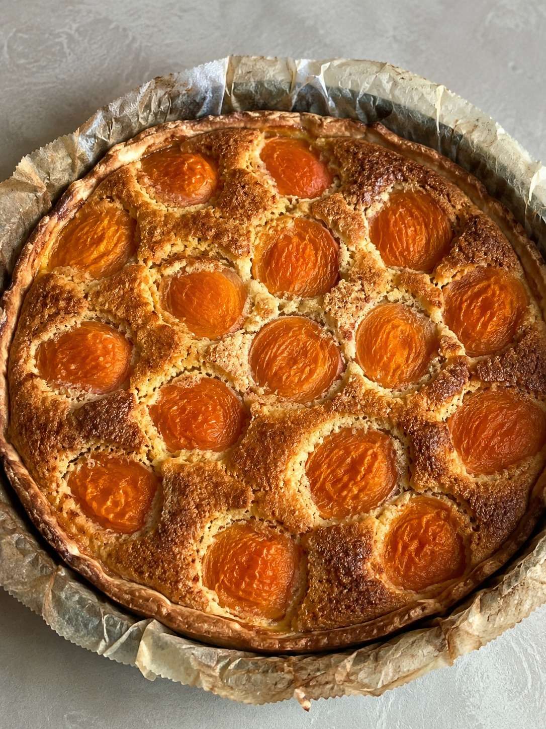 Tarte amandine aux abricots dorée avec crème aux amandes fondante et abricots caramélisés dans un moule rustique