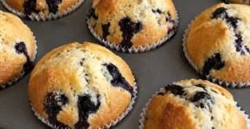 Muffins maison aux myrtilles moelleux et dorés servis sur une table avec quelques myrtilles fraîches