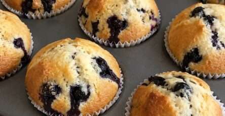 Muffins maison aux myrtilles moelleux et dorés servis sur une table avec quelques myrtilles fraîches