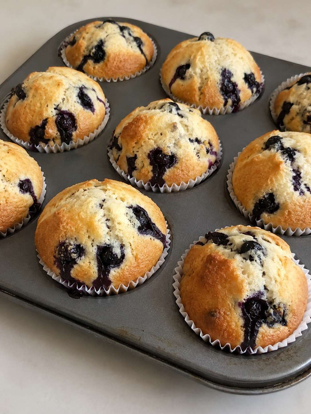 Muffins maison aux myrtilles moelleux et dorés servis sur une table avec quelques myrtilles fraîches