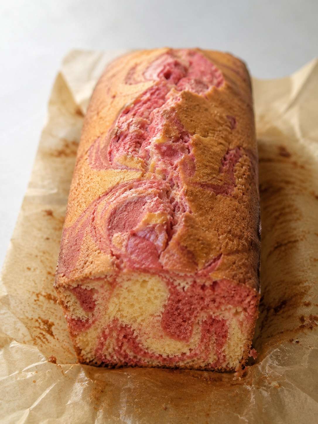 Cake marbré vanille-fraise moelleux avec spirales roses et vanillées dans un moule à cake maison gourmand