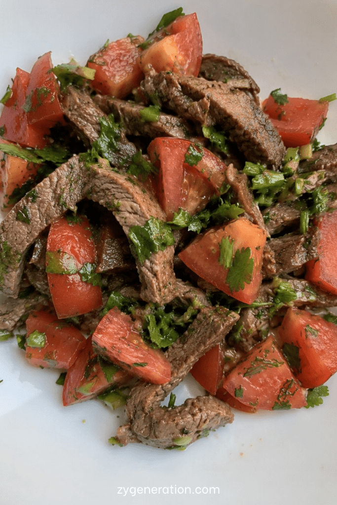 Salade fraîche au bœuf avec tomates, herbes fraîches et citron dans un grand saladier estival coloré