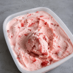 Glace maison à la fraise sans sorbetière, servie en boules crémeuses avec une couleur rose naturelle et des fraises fraîches.
