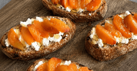 Bruschettas dorées garnies de fromage de chèvre frais, fines tranches d’abricots, filet de miel et poivre sur pain grillé.