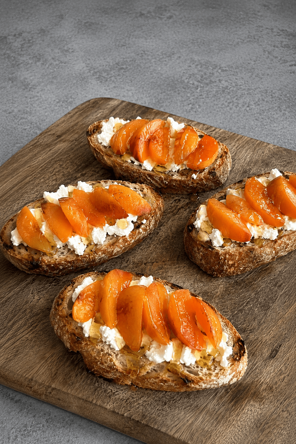 Bruschettas dorées garnies de fromage de chèvre frais, fines tranches d’abricots, filet de miel et poivre sur pain grillé.