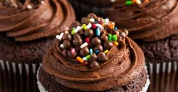 Cupcakes au chocolat faits maison avec glaçage chocolat fondant, décorations colorées et texture moelleuse, présentés sur une assiette de dessert.