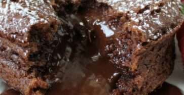 Fondant au chocolat individuel avec cœur coulant, saupoudré de sucre glace et décoré de fraises fraîches dans une assiette de dessert.