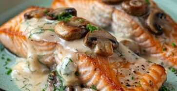 Pavé de saumon farci aux champignons, nappé d’une sauce crémeuse, servi avec du persil frais et un accompagnement de riz.