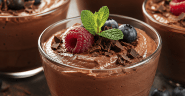 Verrines de mousse au chocolat noir à la texture soyeuse et aérienne, décorées de copeaux de chocolat et servies bien fraîches.