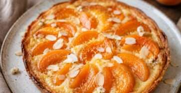 Tarte fine en pâte feuilletée garnie de crème d’amande fondante, de quartiers d’abricots rôtis et d’amandes effilées dorées au four.