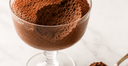 Mousse au chocolat aérienne servie dans des verrines en verre, avec une texture légère et mousseuse, des copeaux de chocolat noir et une fine couche de cacao.
