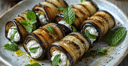 Roulés d’aubergine grillée garnis de ricotta crémeuse et de menthe fraîche, disposés sur une assiette en céramique avec de l’huile d’olive et du citron.