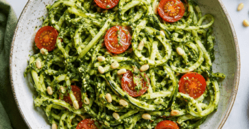 Spaghetti de courgette crue enrobés de pesto vert maison, garnis de tomates cerises colorées, de pignons grillés, de parmesan et de basilic frais.