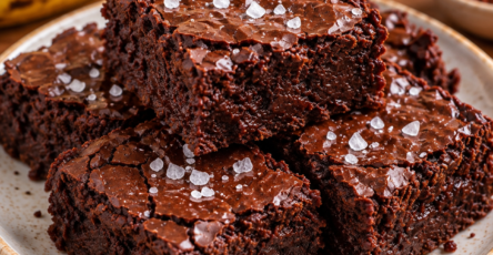 Brownie fondant sans farine découpé en carrés, préparé avec bananes mûres, beurre de cacahuète et cacao, avec une pincée de fleur de sel.