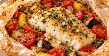 Dos de cabillaud cuit en papillote avec aubergine, tomates, poivron, huile d’olive et herbes méditerranéennes, servi chaud.